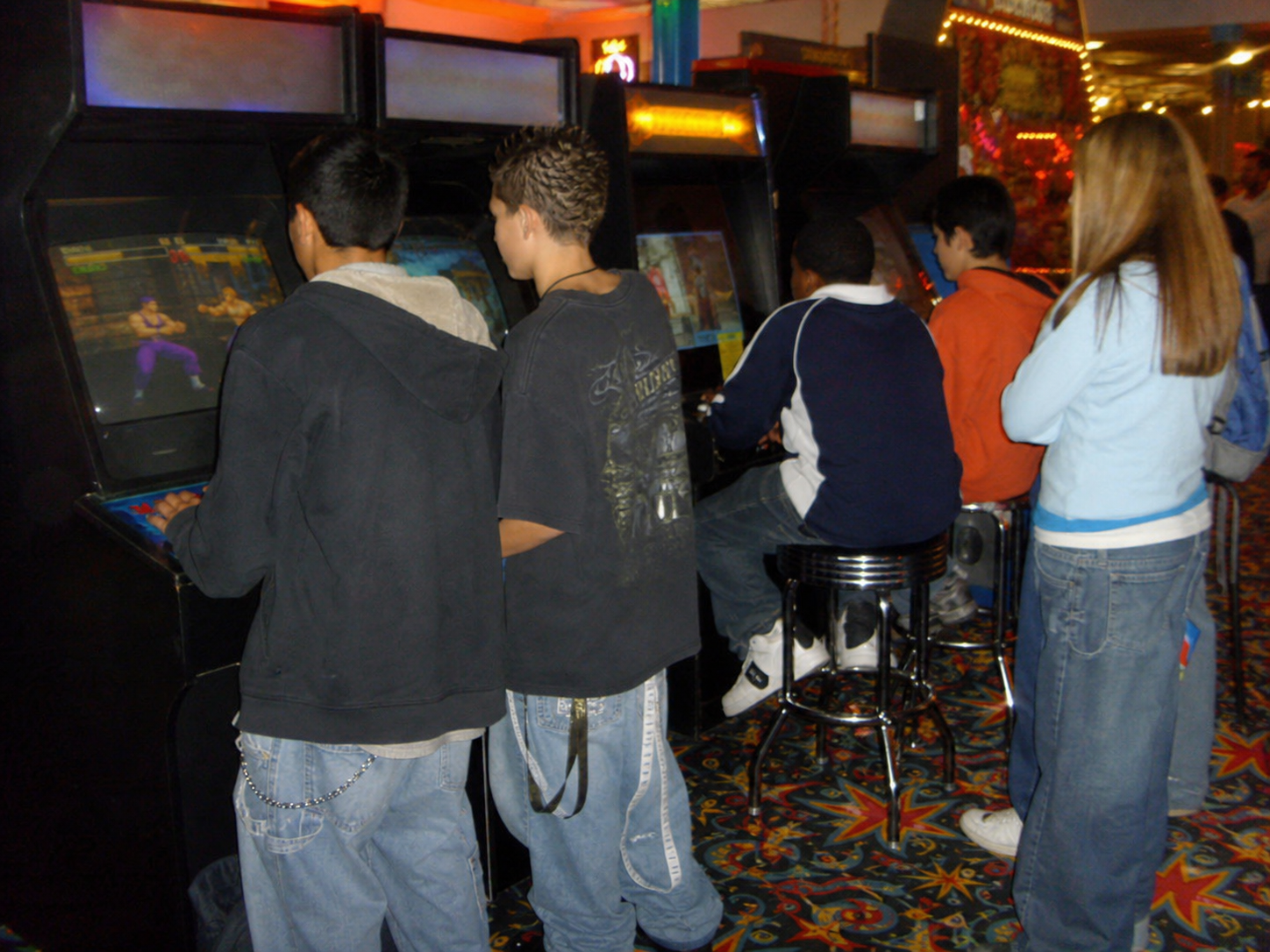 Teenagers playing arcade cabinets during game night